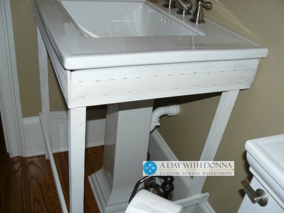 You will want the back legs of your pedestal sink framework to clear any floor molding.  The legs are not flush with the wall, but flush with the floor mold.  