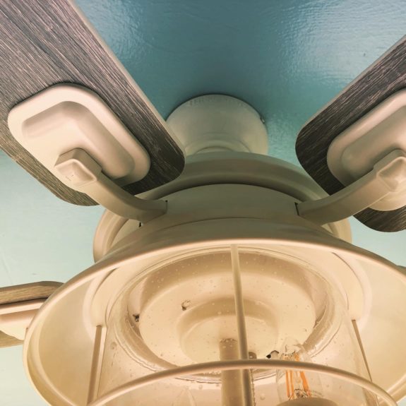 A soft white ceiling fan against a blue porch ceiling